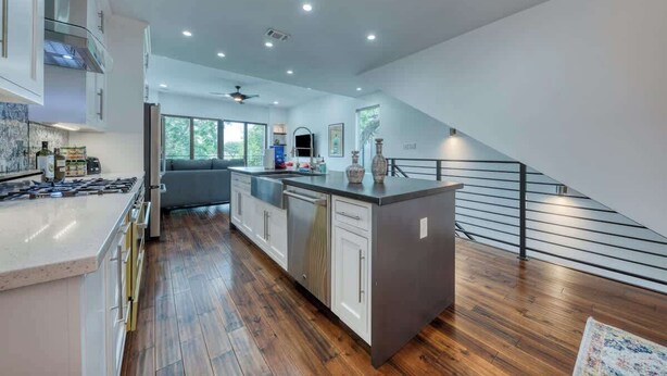 Une cuisine moderne dotée d’un îlot central, de planchers en bois et d’un escalier menant à un niveau supérieur.