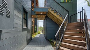 A narrow pathway leading to a wooden staircase with a metal railing. - Urban Modern Luxury Group Rental in Lavaca (San Antonio)