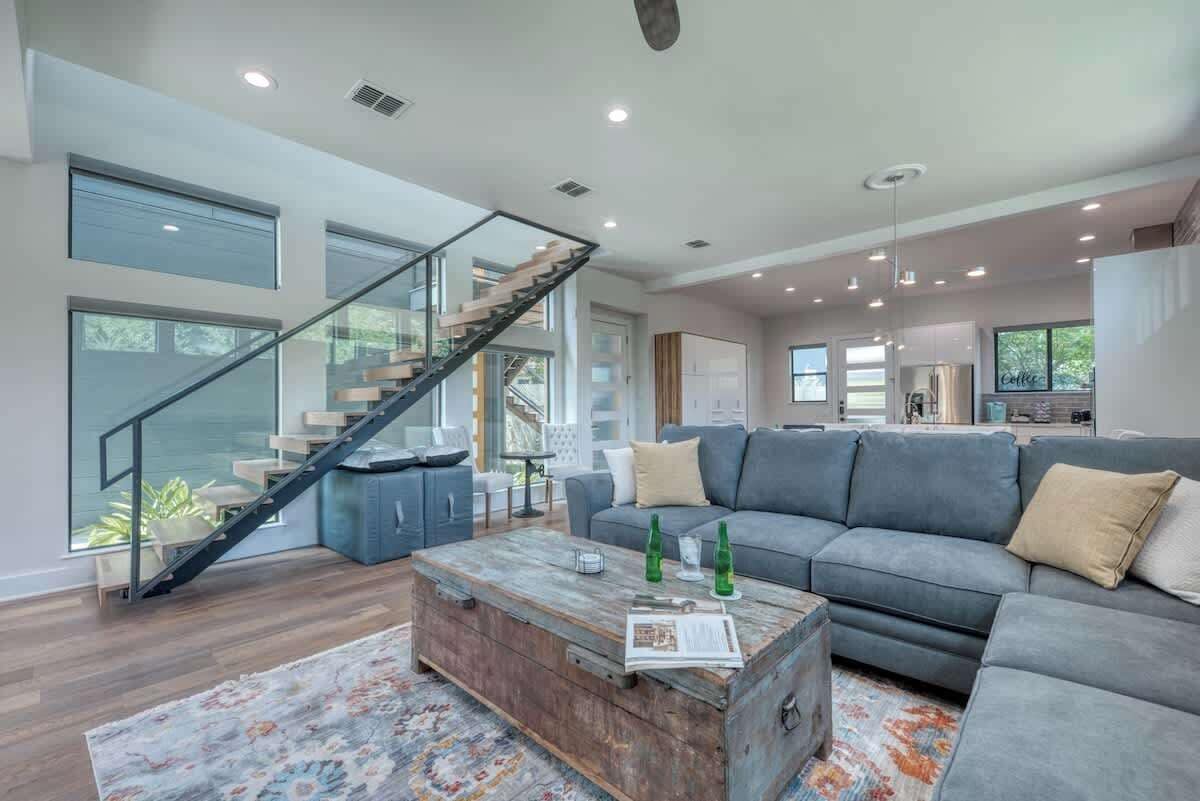 A spacious living area with a modern staircase, a grey sofa, and a wooden coffee table.