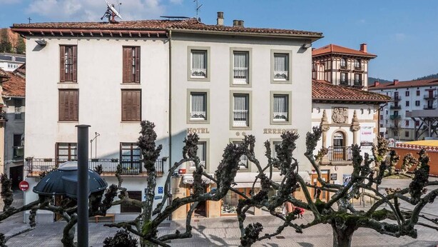 Un hôtel à la façade blanche, doté de nombreuses fenêtres et d’un balcon.
