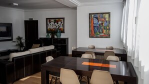 Une salle de réunion moderne équipée d’une grande table, de chaises, d’un canapé et d’un téléviseur.