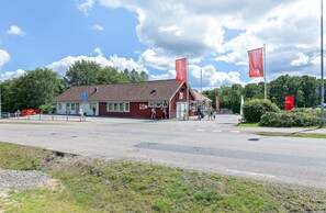 A red building with a sloped roof, a blue sign, and red flags.