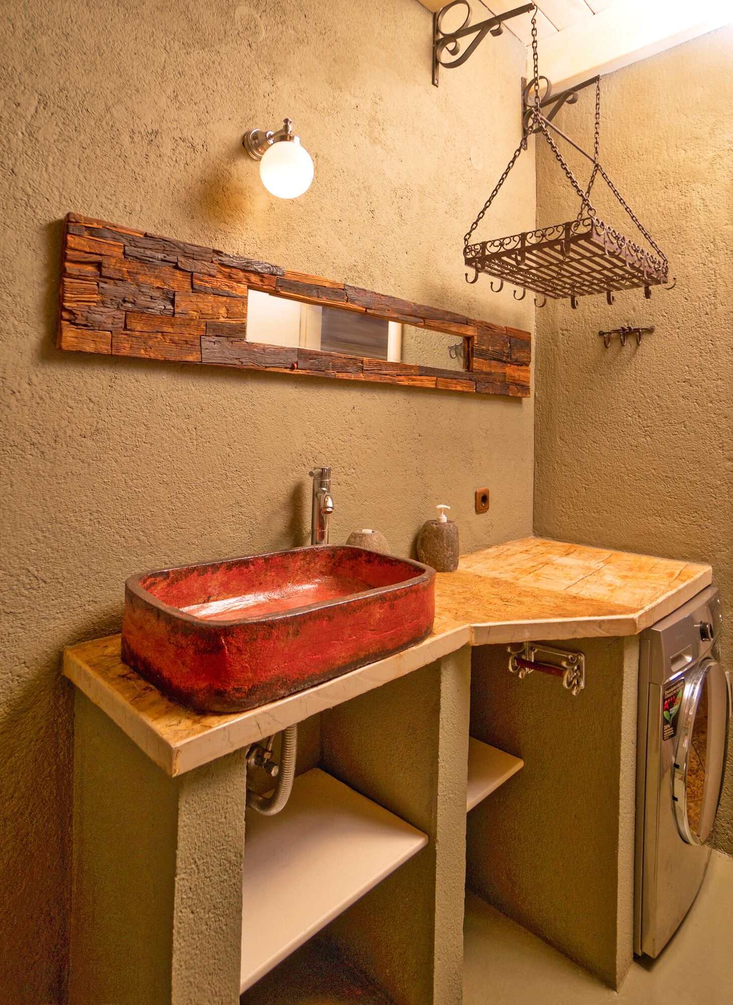 Un baño de diseño rústico, con un espejo de marco de madera, un lavabo rojo y una lámpara colgante de estilo vintage.