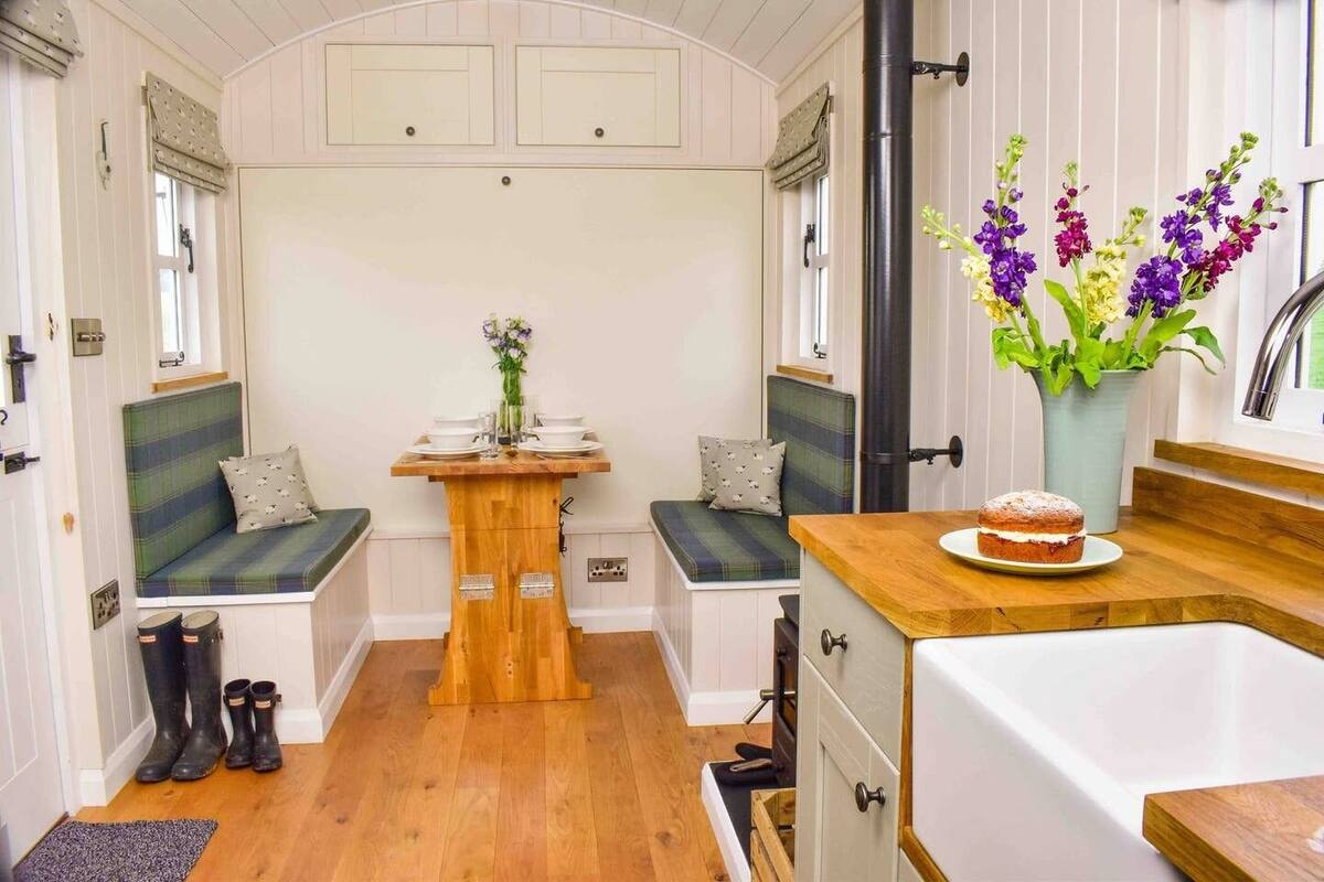 A compact kitchen with a wooden table, seating, and a sink.