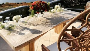 Een houten tafel gedekt met bloemen en kaarsen, met uitzicht op een bergachtig landschap.