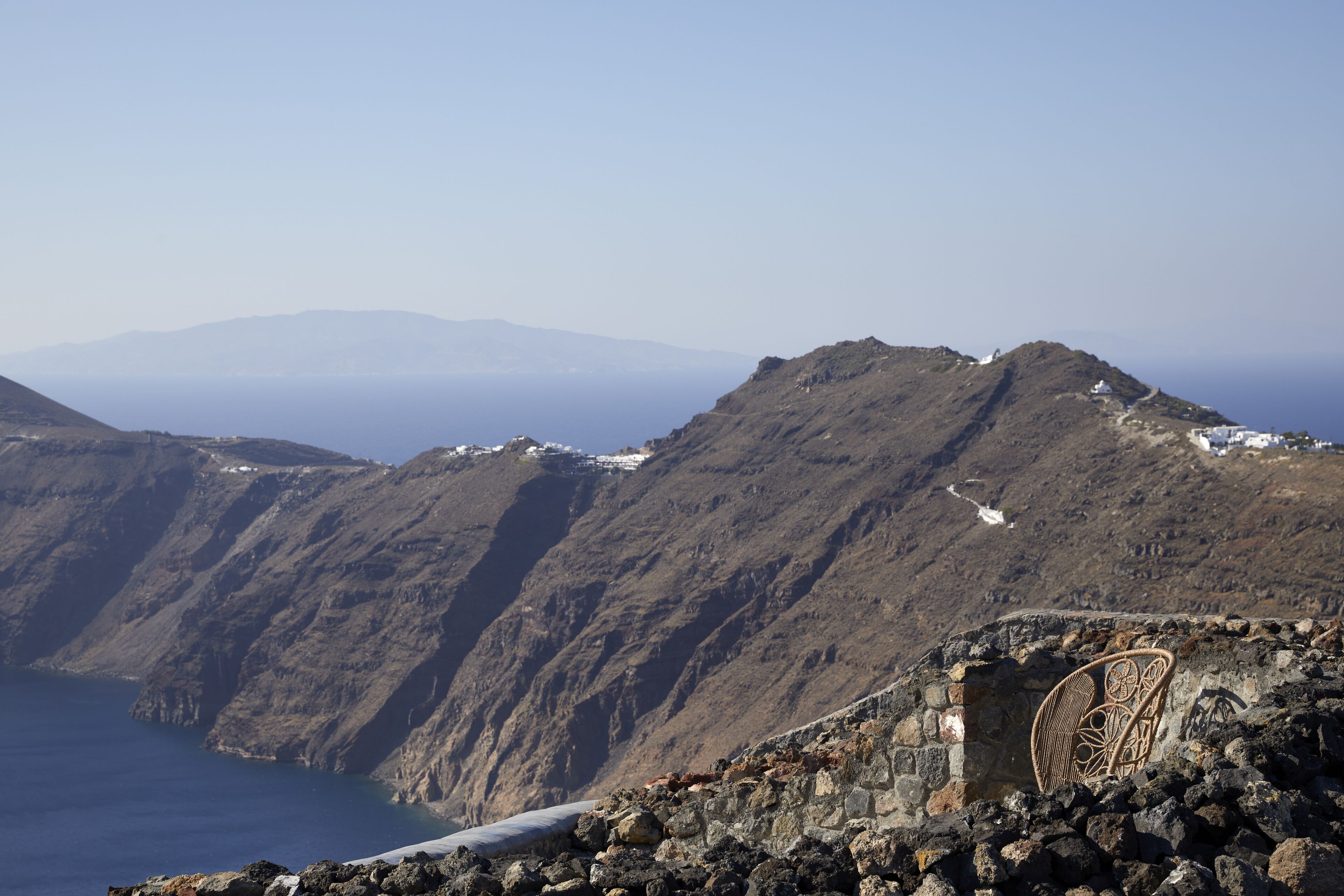 A rugged mountain landscape with a stone wall and a wicker chair.