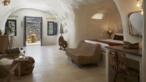 Een gezellig, modern interieur met een stenen muur, een rieten bank, een houten eettafel en een grote spiegel.