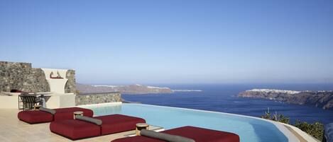 Una piscina al aire libre, sombrillas, sillones reclinables de piscina