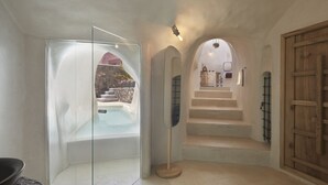 Een moderne badkamer met een douchecabine van glas, een houten vloer en een trap naar een slaapkamer.