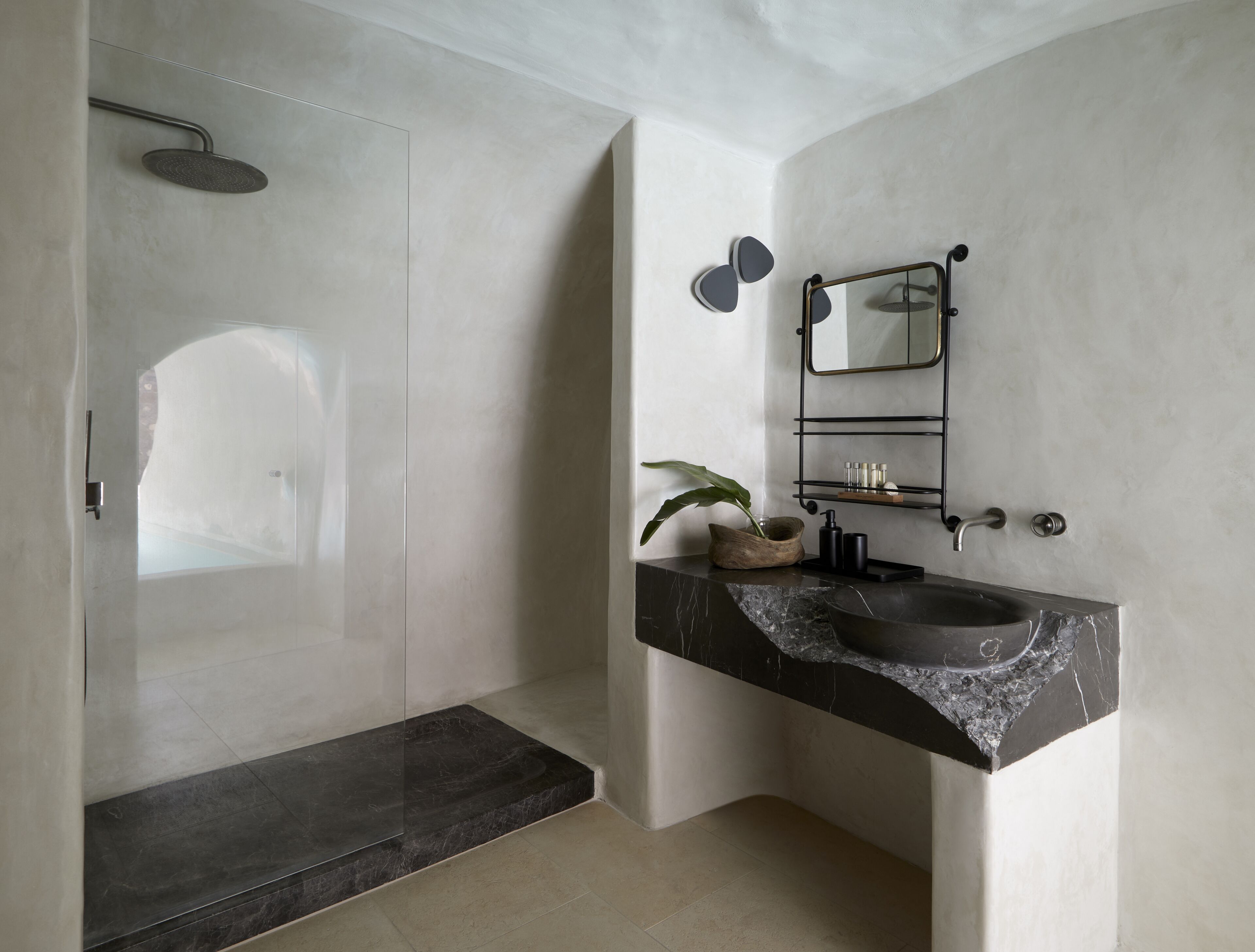 A modern bathroom with a glass-enclosed shower, a marble sink, and a minimalist design.