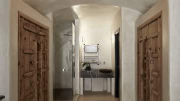 Stylish hallway leads to a bathroom with a glass shower enclosure, sink, and mirror.