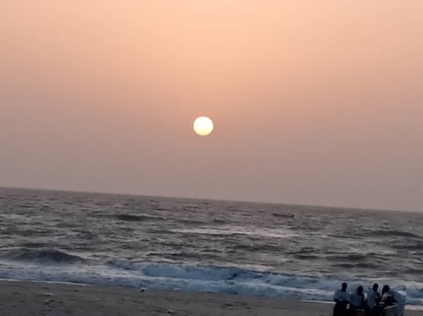 A beach scene with a sunset over the ocean.