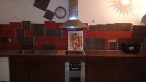 A kitchen with a central island, a clock, and a decorative wall piece. - Eden Beach Saint-Louis (St. Louis)