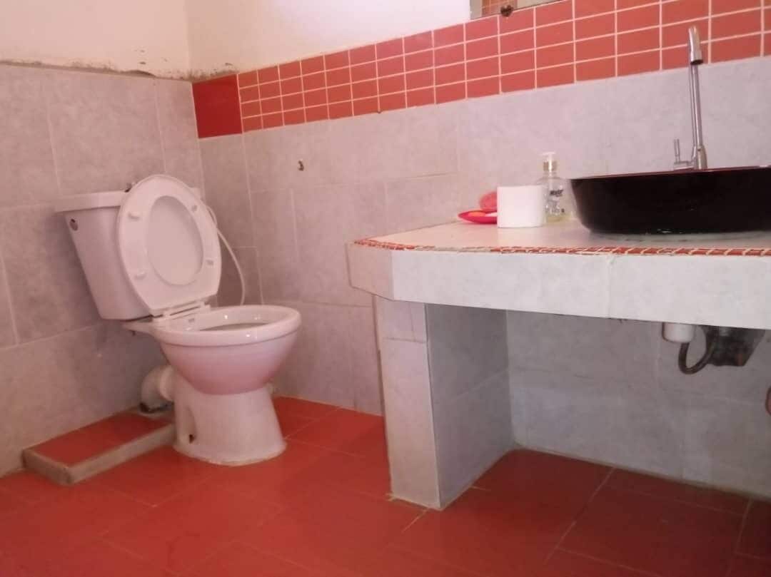 A bathroom with a toilet, sink, and red-tiled floor.