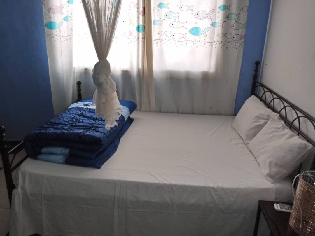 Une chambre à coucher avec un lit, une table de chevet, une lampe et des rideaux à motifs de poissons.