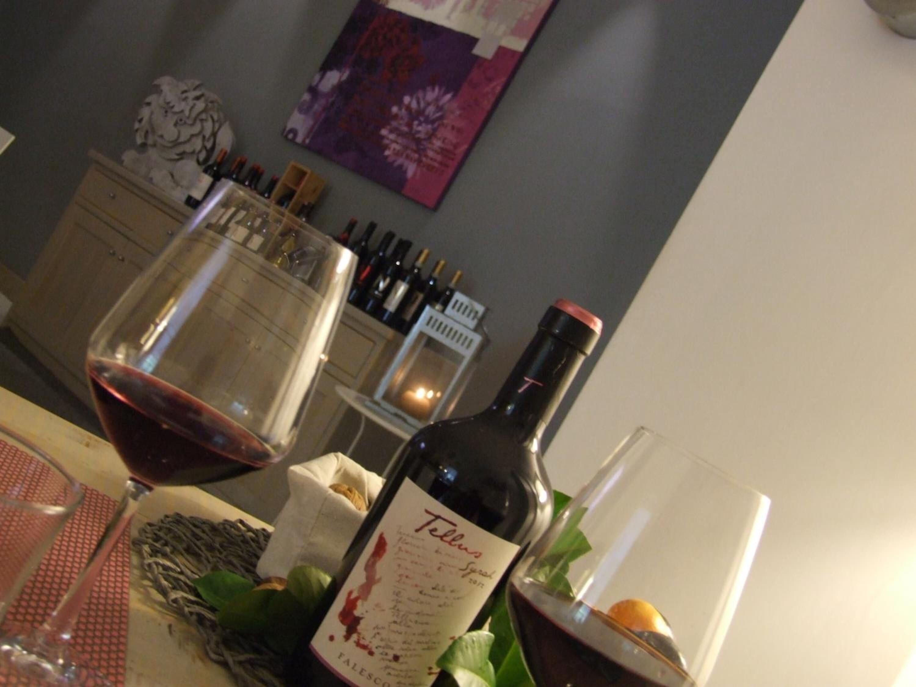 Una mesa con una botella de vino, una copa de vino tinto y una vela.