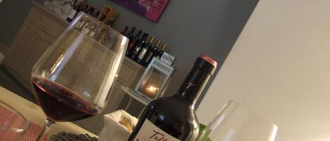 Una mesa con una botella de vino, una copa de vino tinto y una vela.