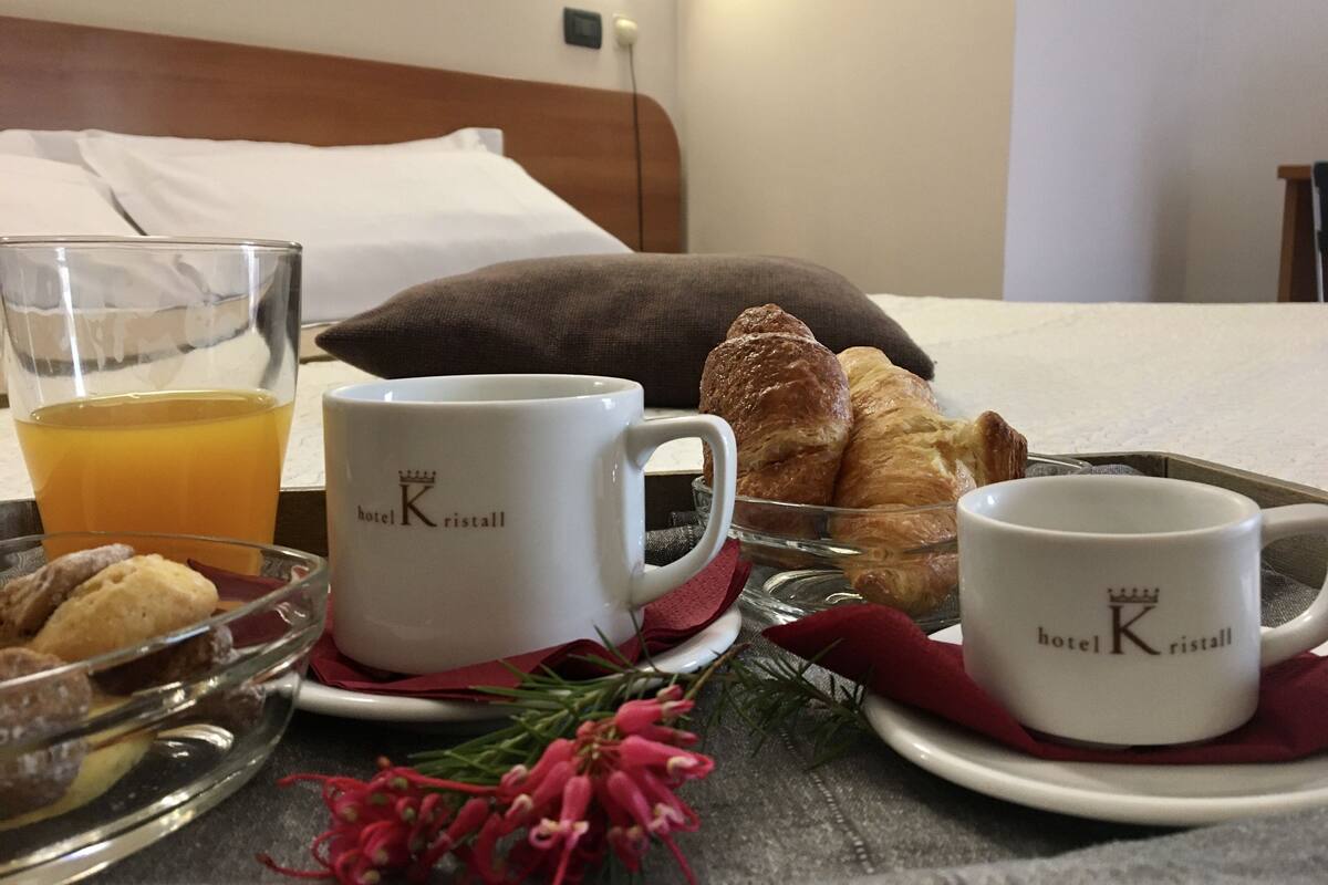 Un plateau de petit-déjeuner comprenant des croissants, un verre de jus d’orange et deux tasses ornées du logo de l’hôtel.
