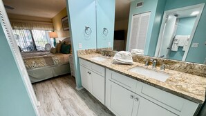 Un baño con un espejo grande, dos lavamanos y una cama con vista al exterior.