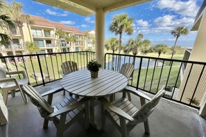 A balcony with a round table and chairs, overlooking a pool and a building with balconies. - ENJOY FREE FUN DAILY & a tranquil Silver-rated condo with views of the ocean and lagoon. (Saint Augustine)