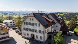 Un hotel con fachada tradicional, paneles solares en el techo y vistas del campo circundante.