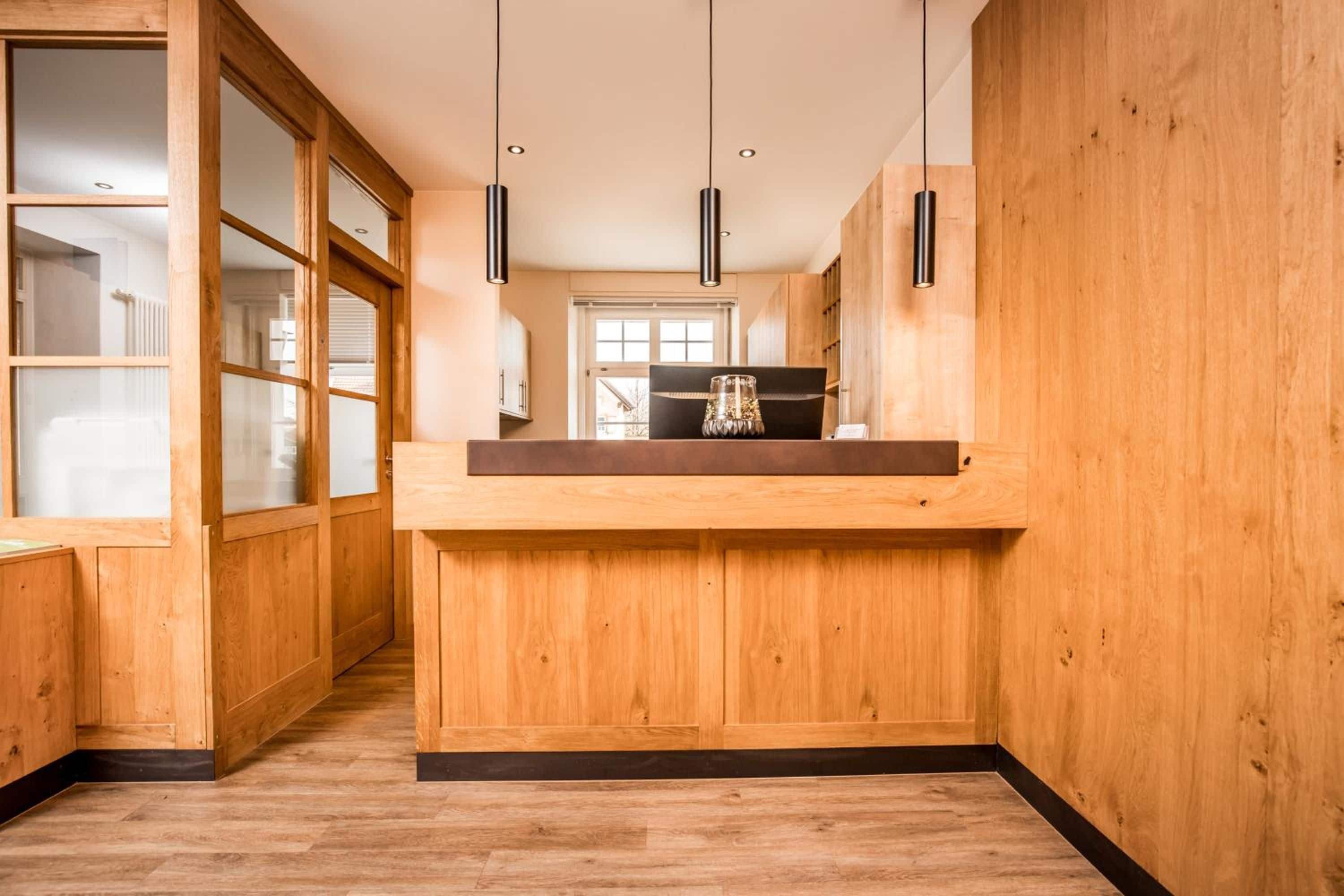 A kitchen with wooden cabinetry, a central island, pendant lighting, and a view into the adjacent living area.