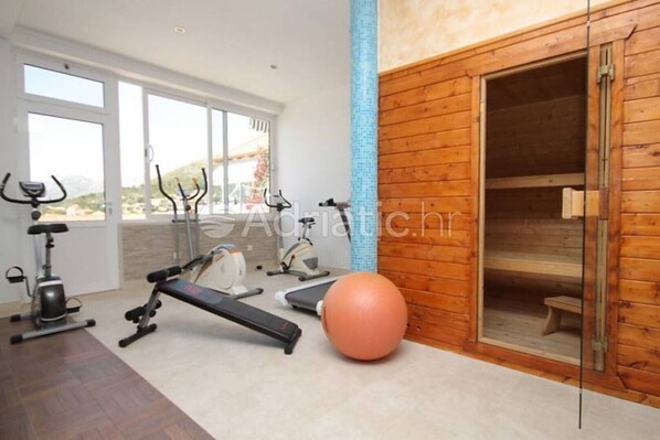A gym with exercise equipment, a large exercise ball, and a sauna.