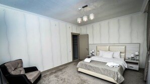 A hotel room with a bed, bedside tables, a chair, and a wardrobe. - Qafqaz Yeddi Gozel Resort (Gabala)