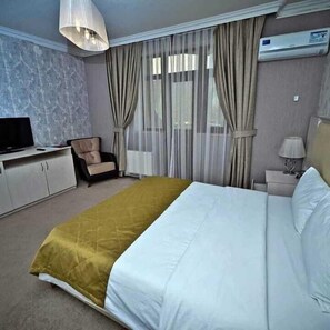 A hotel room with a bed, a chair, a TV, an air conditioner, and a lamp. - Qafqaz Yeddi Gozel Resort (Gabala)
