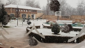 A snow-covered courtyard with a building, a bridge, and a fountain. - Qafqaz Yeddi Gozel Resort (Gabala)