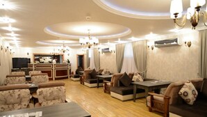 A spacious lounge area with sofas, armchairs, and tables. There is a bar area in the background. - Qafqaz Yeddi Gozel Resort (Gabala)