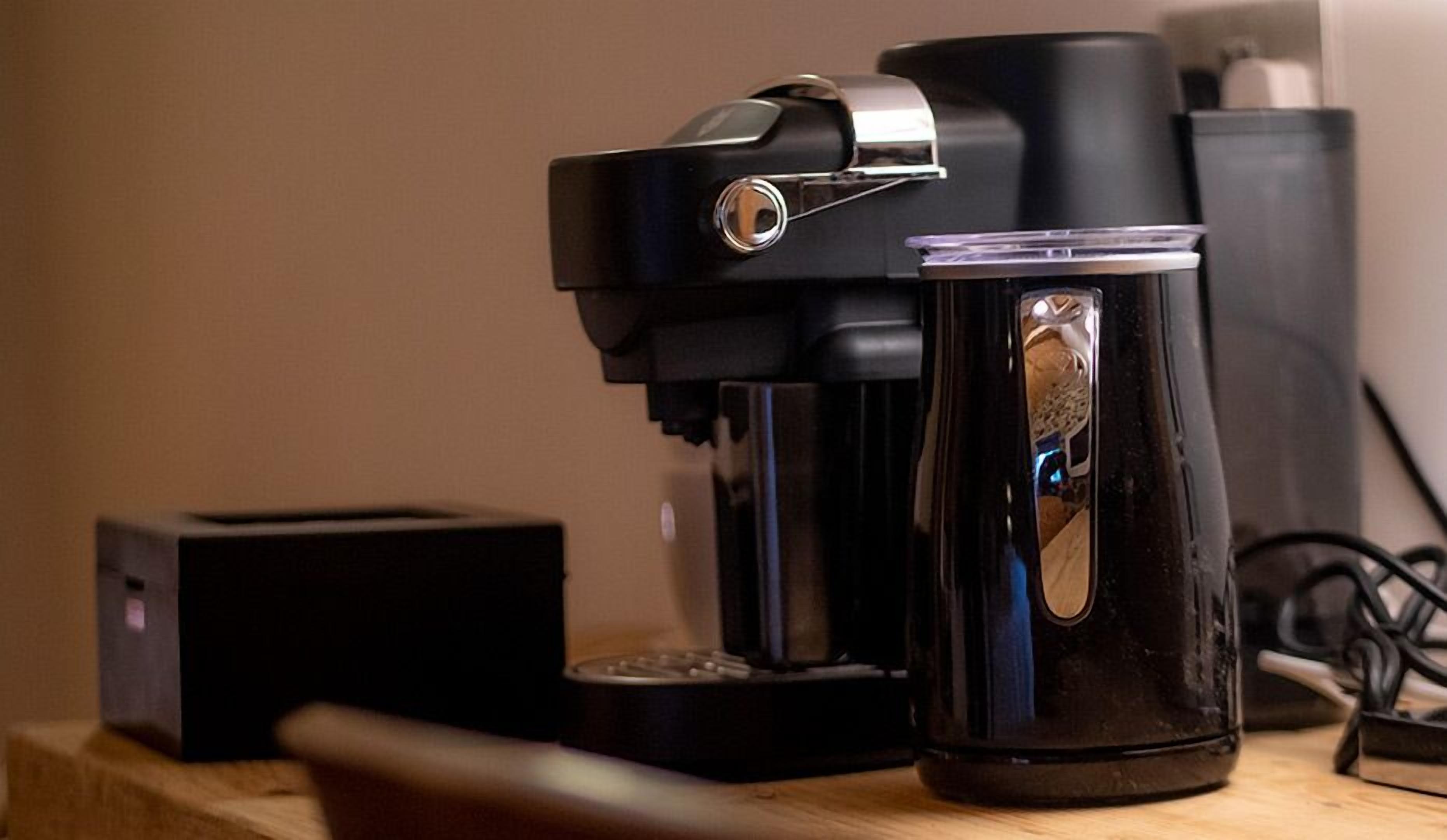 A coffee maker and a mug on a wooden surface.