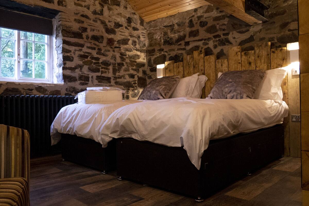 A stone-walled bedroom with a bed, a window, and a radiator.