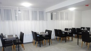 A conference room with multiple tables and chairs, white curtains, and a tiled floor. - Budget Hotel Ludwigshafen (Ludwigshafen)