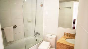 A bathroom with a glass-enclosed shower, a toilet, and a sink.