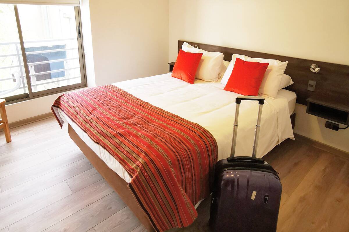 Een hotelkamer met een bed, een koffer en een raam met uitzicht.