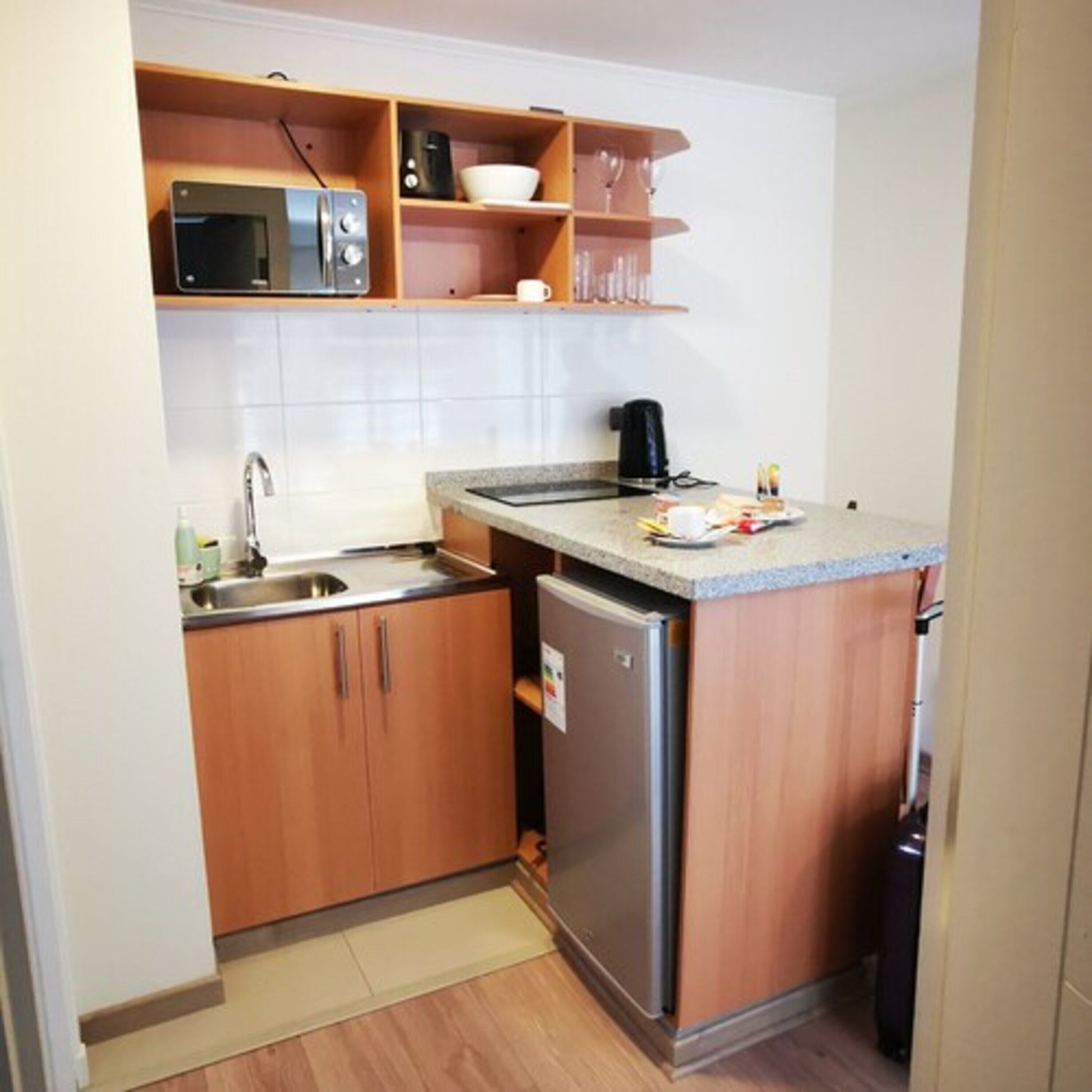 A compact kitchen with a microwave, coffee maker, and a small refrigerator.