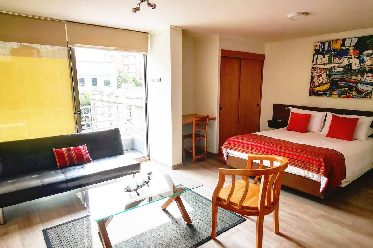 Een hotelkamer met een bed, een bank, een eettafel en een stoel.