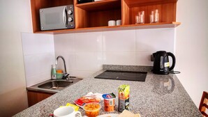 Una cucina con un piano di lavoro in granito, un forno a microonde, una macchina da caffè e un lavello.
