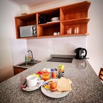 Une cuisine équipée d’un plan de travail en granit, d’un four à micro-ondes, d’une machine à café et d’un évier.
