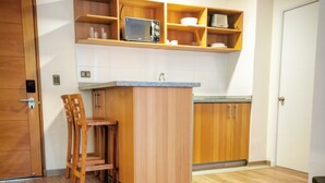 Una cucina compatta con mobili in legno, un forno a microonde e un piccolo angolo ristoro con una sedia.