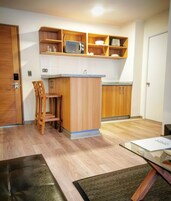 Une cuisine compacte avec des meubles en bois, un four à micro-ondes et un petit coin repas équipé d’une chaise.