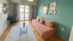 A living room with a sofa, a coffee table, and a dining area with a table and chairs. - Check Point - Syngrou Fix (Athens)