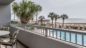 Ein Balkon mit Pool, der Blick auf einen Strand mit Palmen und einer Laube freigibt.