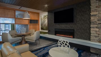 Una sala moderna con chimenea, asientos cómodos y un televisor grande.