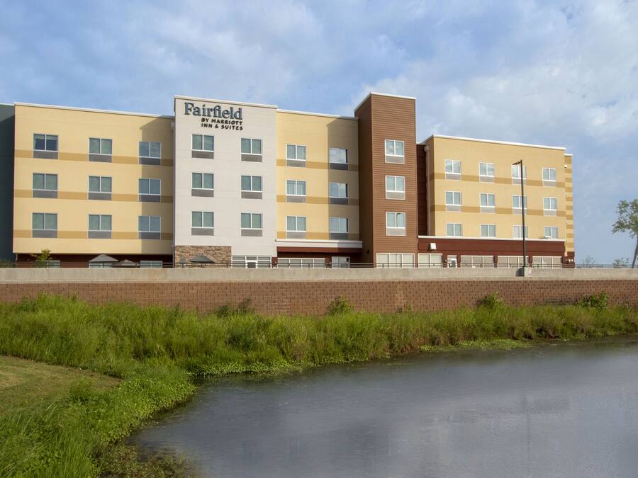 Ein mehrstöckiges Hotel mit schlichter Fassade, zahlreichen Fenstern und einem Schild, das es als Fairfield Inn & Suites kennzeichnet.