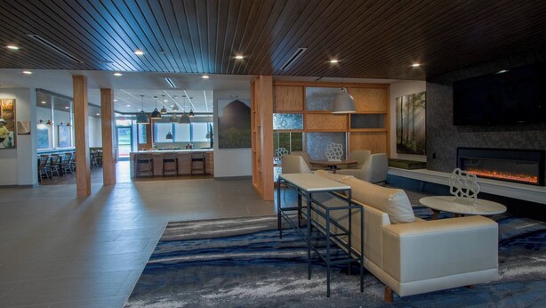 A spacious living area with a modern fireplace, a seating area with a sofa and coffee table, and a kitchen in the background.