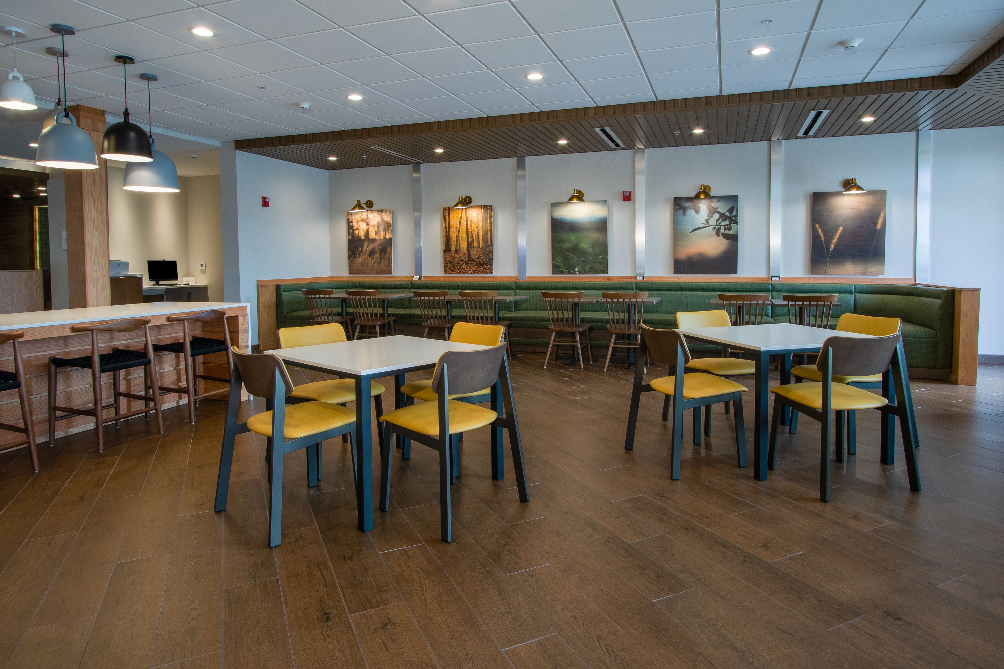 A restaurant with booths and tables, wooden flooring, and artwork on the walls.