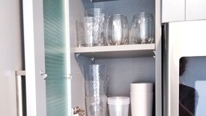 A kitchen with a microwave, a glass cabinet with various glassware, and wooden utensils.