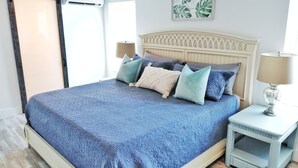 A bedroom with a bed, pillows, a nightstand, and a wall-mounted lamp.